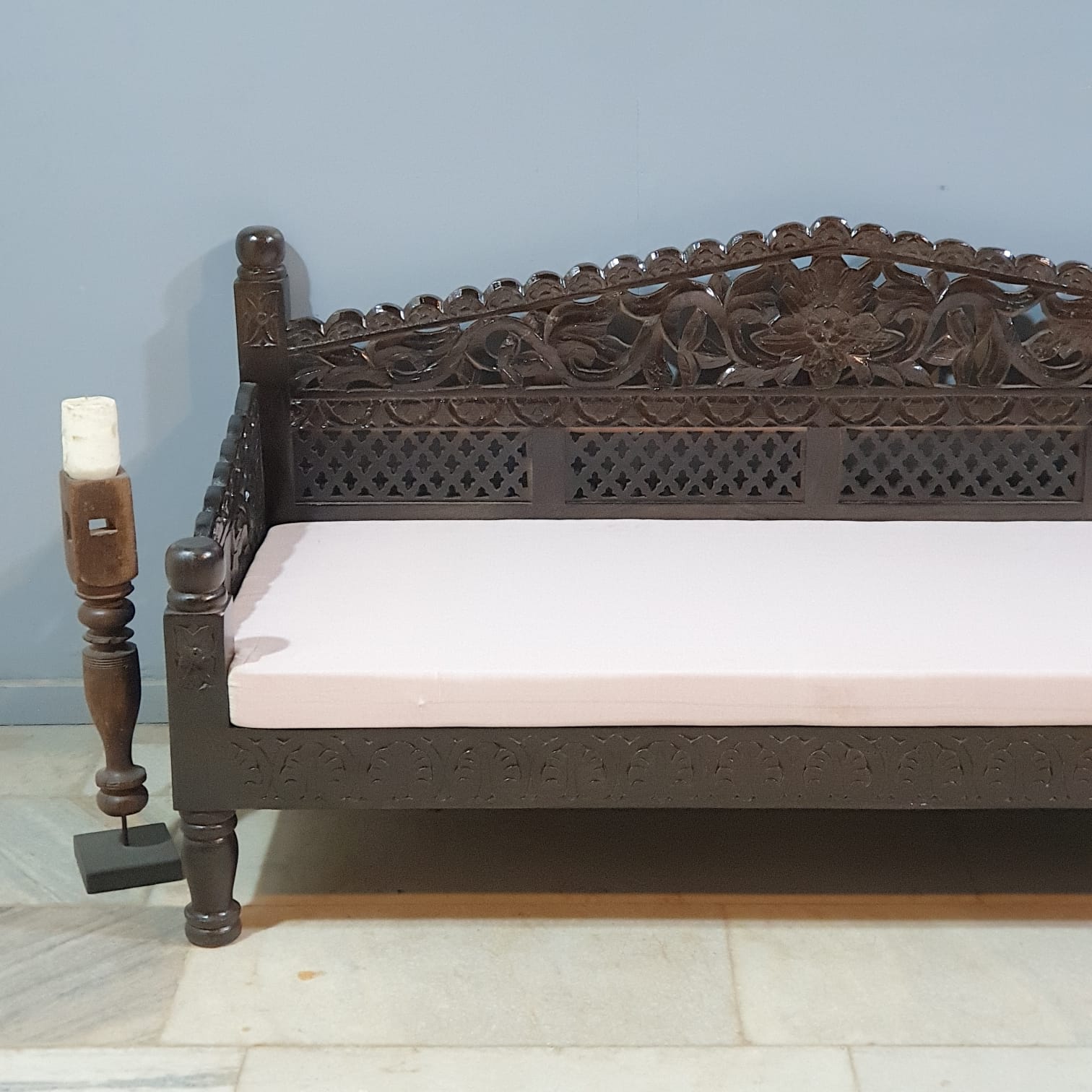 Carved wooden bench with intricate patterns on a light blue wall background