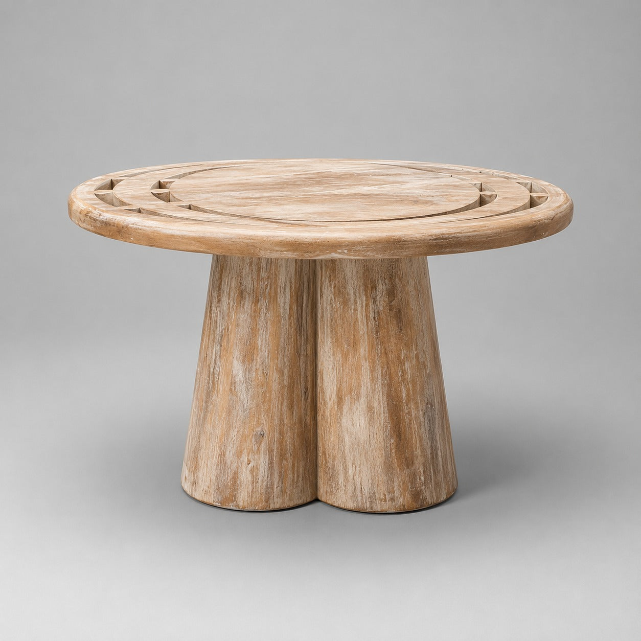 A round wooden side table with a natural weathered finish, featuring a thick two-leg base and decorative cutouts on the tabletop, shown against a neutral gray background.