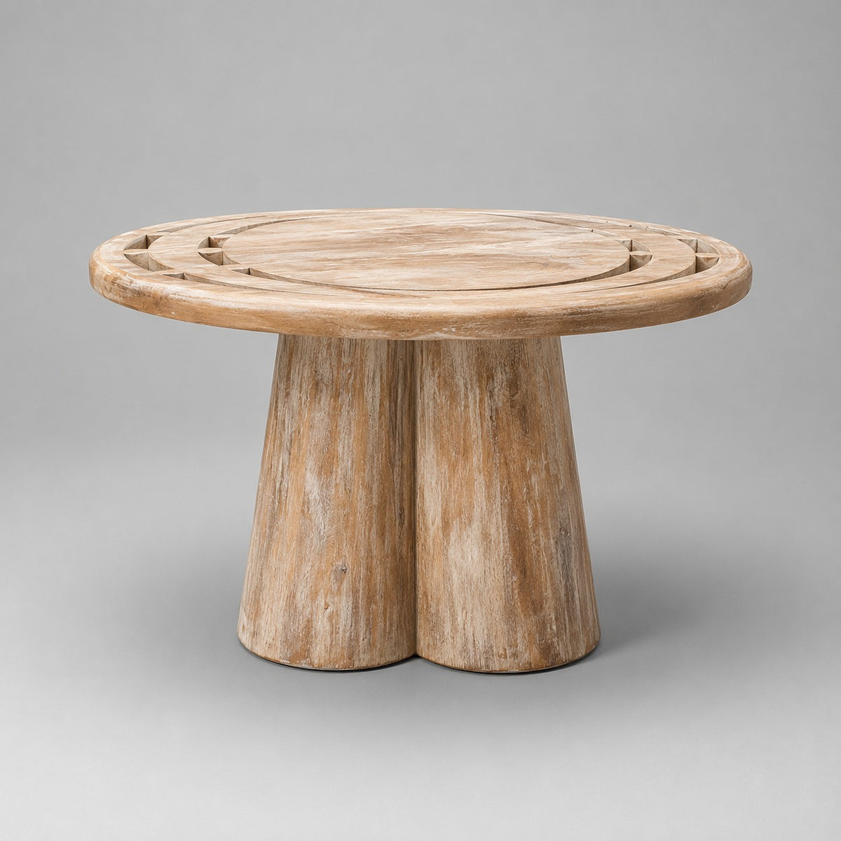 A round wooden side table with a natural weathered finish, featuring a thick two-leg base and decorative cutouts on the tabletop, shown against a neutral gray background.