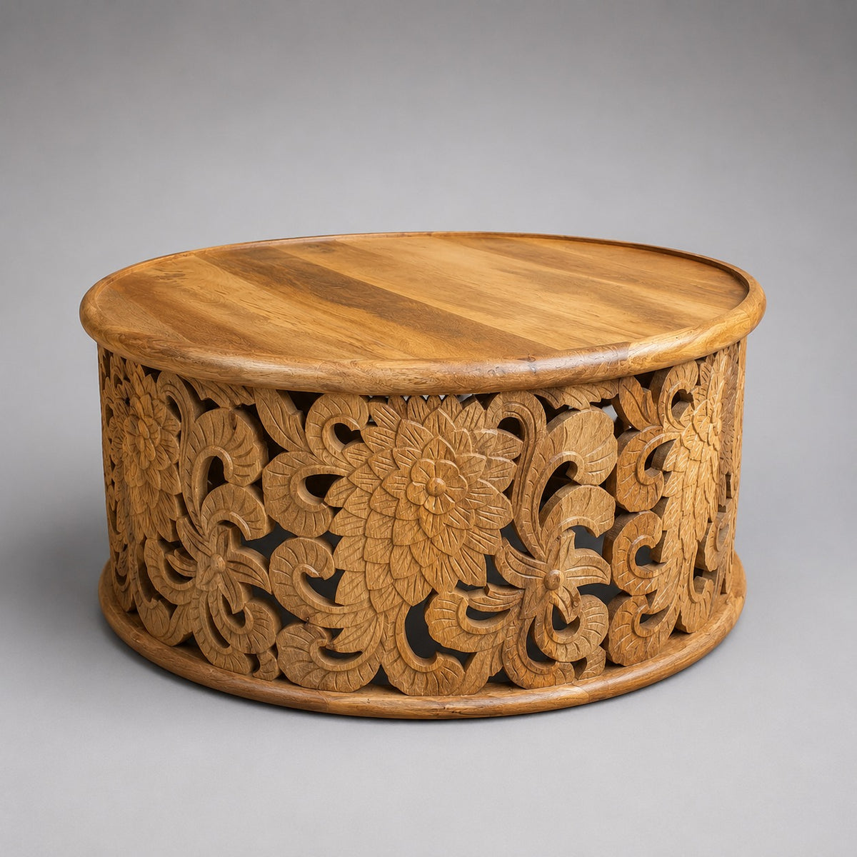 Round mango wood coffee table with intricate hand-carved floral openwork base and natural timber finish.