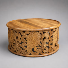 Round mango wood coffee table with intricate hand-carved floral openwork base and natural timber finish.