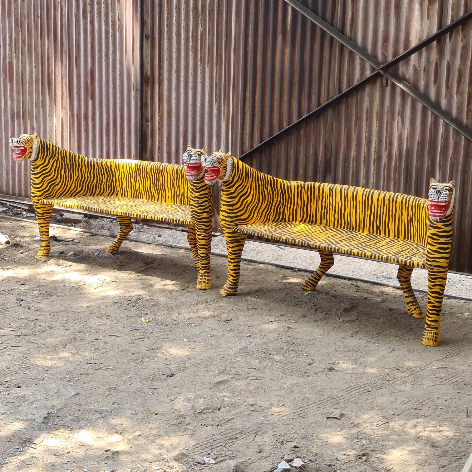 Two tiger-themed benches with striped patterns and red masks on a concrete surface.