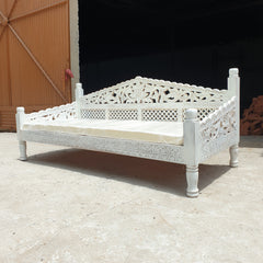 Intricate floral and lattice carving on a whitewash wooden daybed