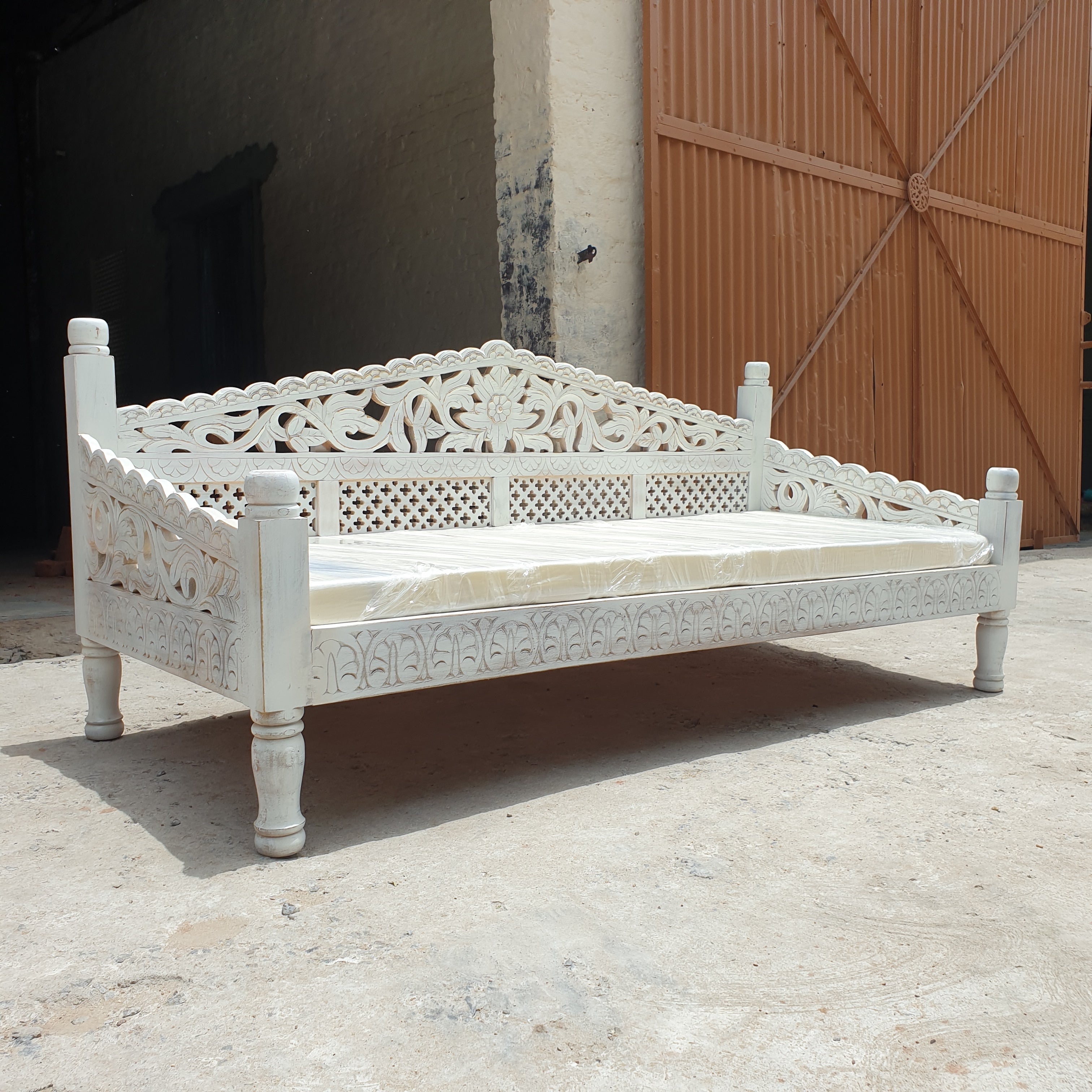 Traditional botanical carvings on the front of a whitewash Indian daybed