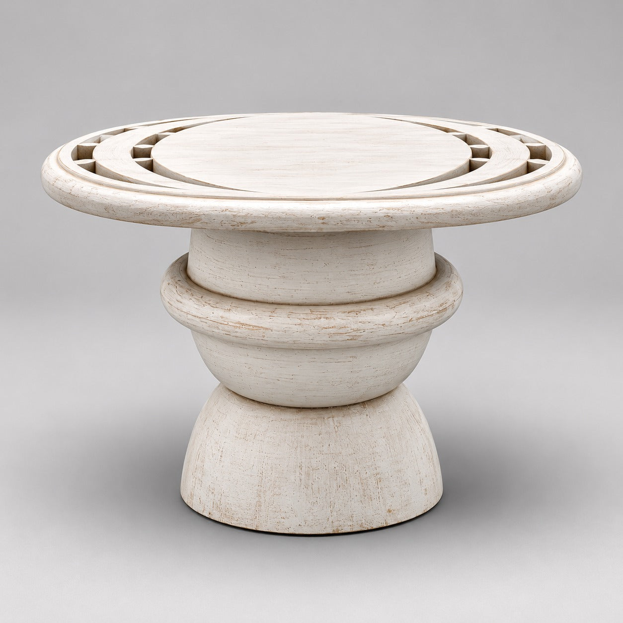 Whitewashed mango wood pedestal coffee table with geometric carved circular top and sculptural rounded base.