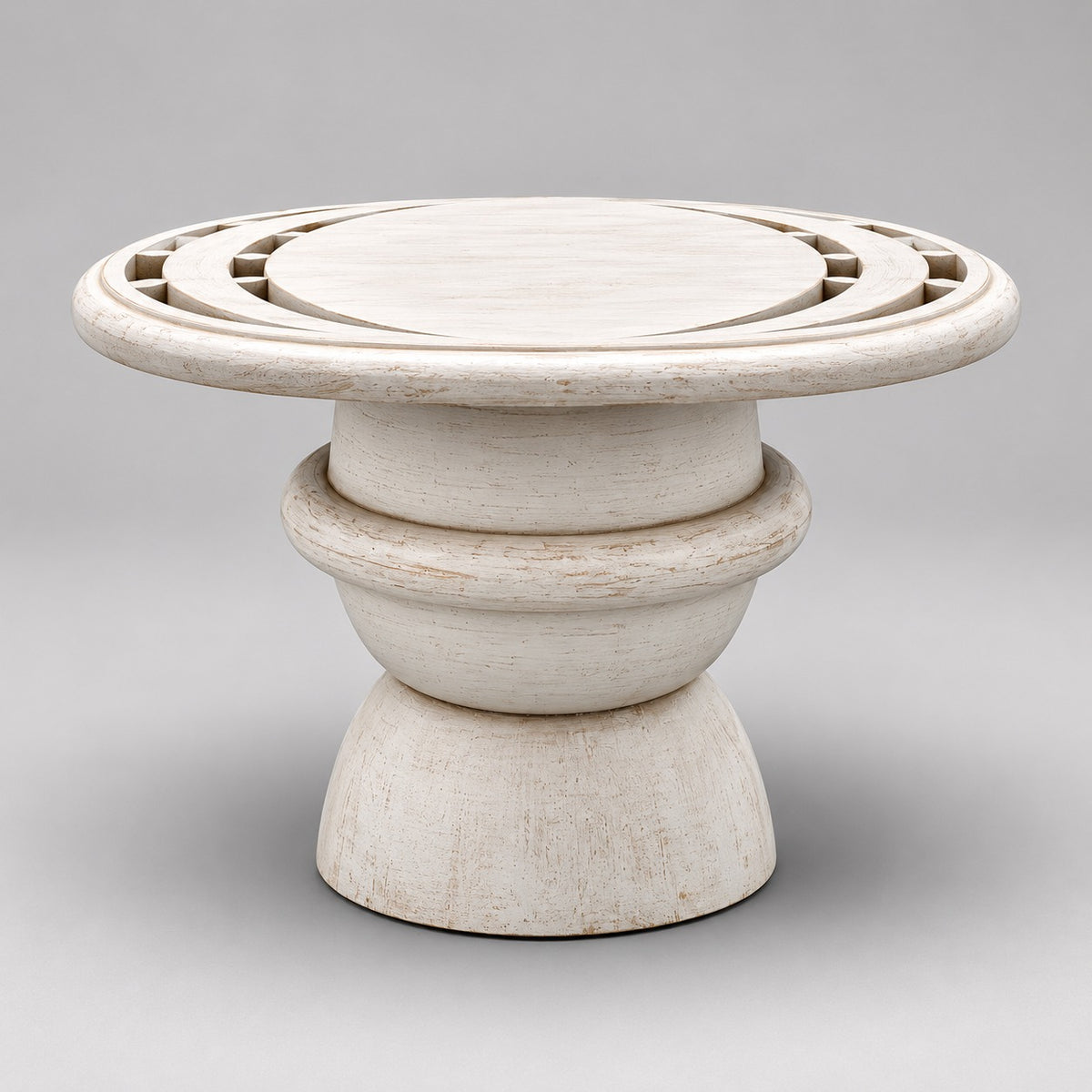 Whitewashed mango wood pedestal coffee table with geometric carved circular top and sculptural rounded base.
