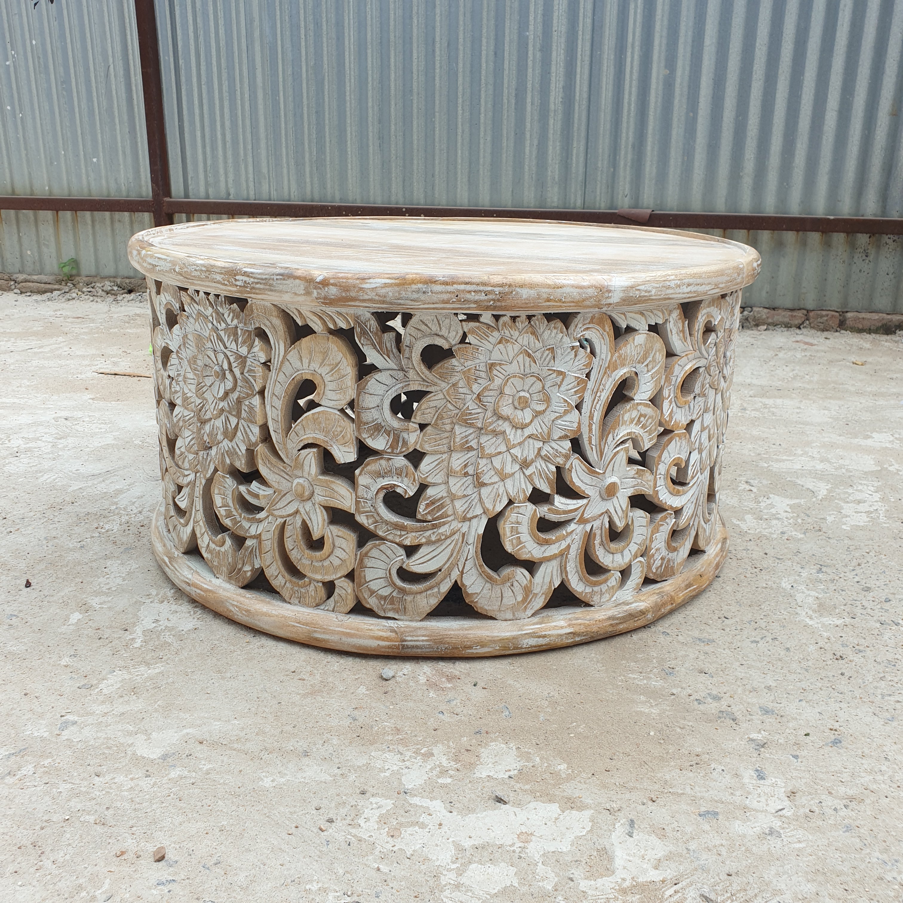 Whitewashed round mango wood coffee table with intricate floral openwork carving, 90 cm diameter.